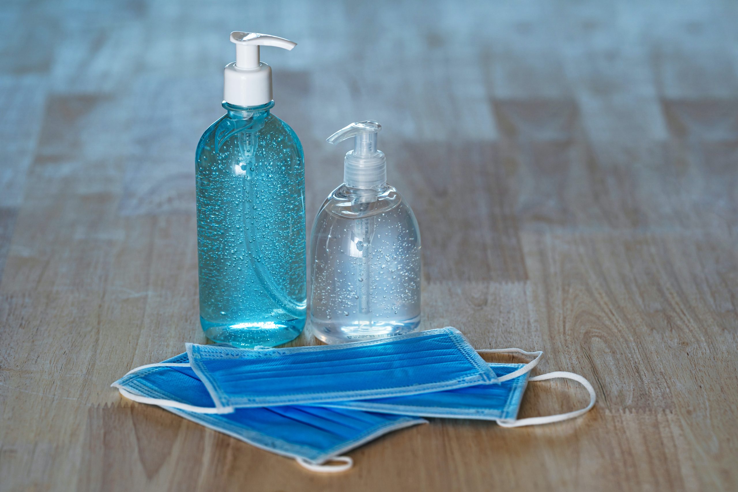 two bottles of hand sanitizer resting on disposable masks - commercial restroom supplies from CLEAN